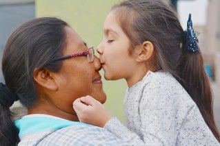 Native American girl kissing older woman