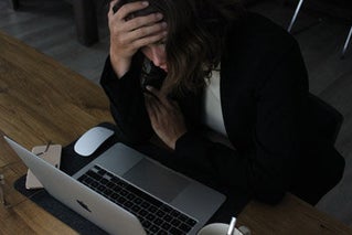 Woman with head in hand looking at computer