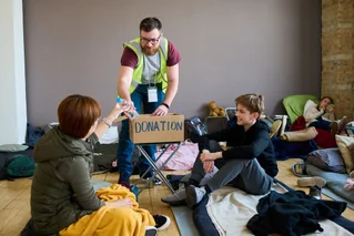 Charity volunteer handing out water to people in a shelter