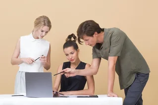 three people looking at computer