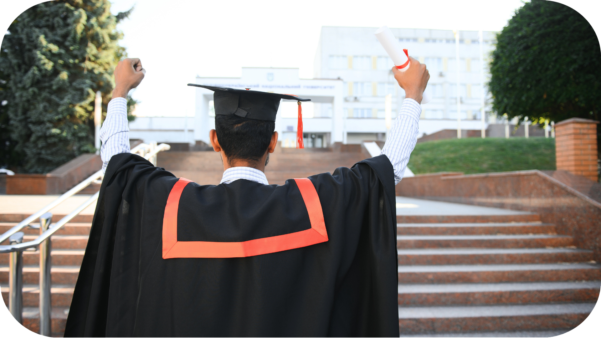 Graduate facing away from the camera, holding diploma in the air